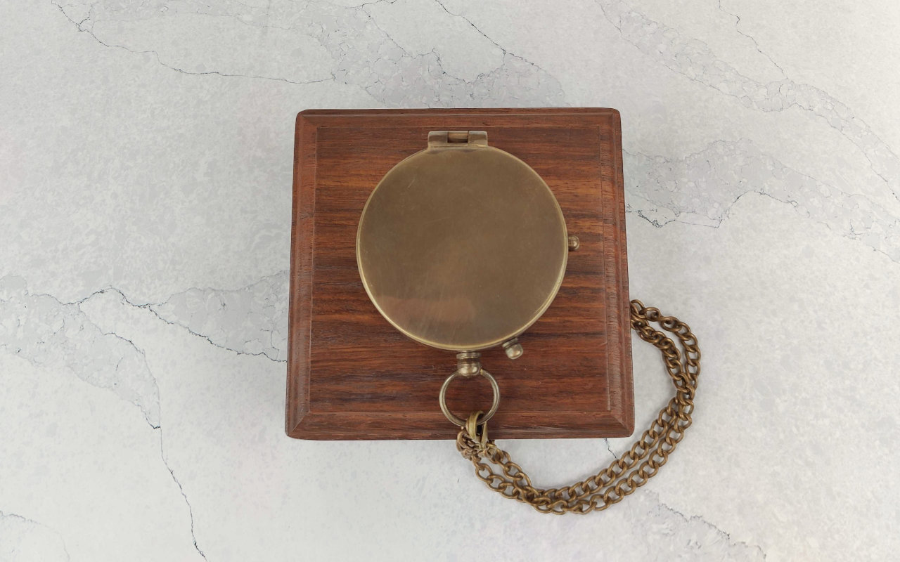 Pohled na gravírované kovové víčko kompasu